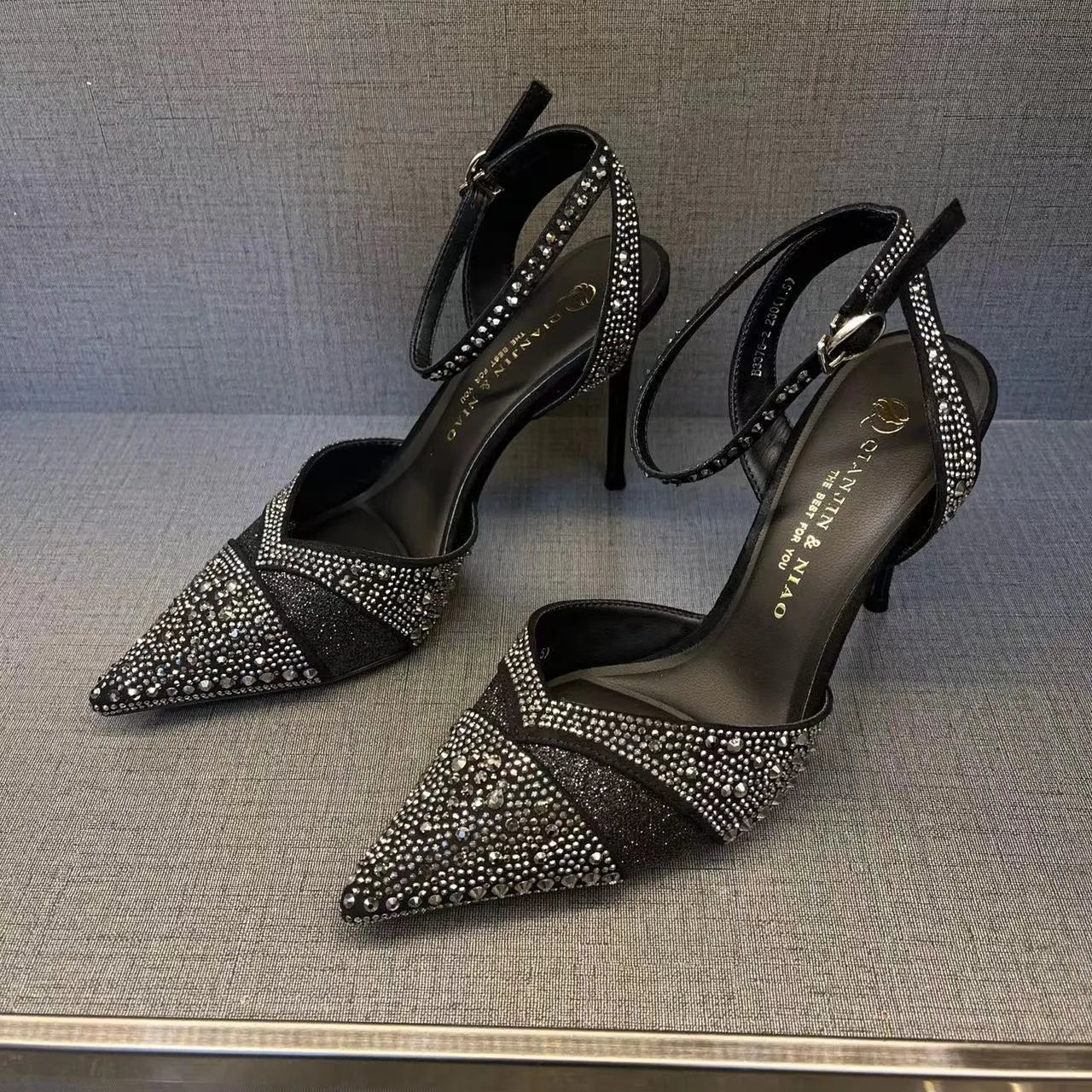 Women's black pointed-toe stiletto heels with a hollow-out design and red sole.