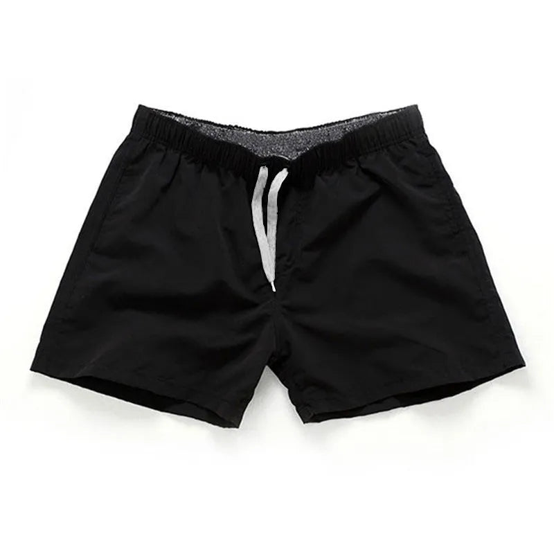 Men's polyester surf shorts in multiple colours on a beach background, showing straight leg design.