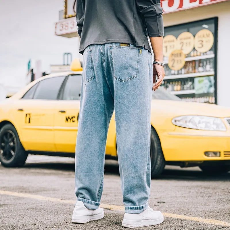 Men's dark blue loose straight-leg cotton jeans on a hanger, showing the simple style and mid-waist fit.