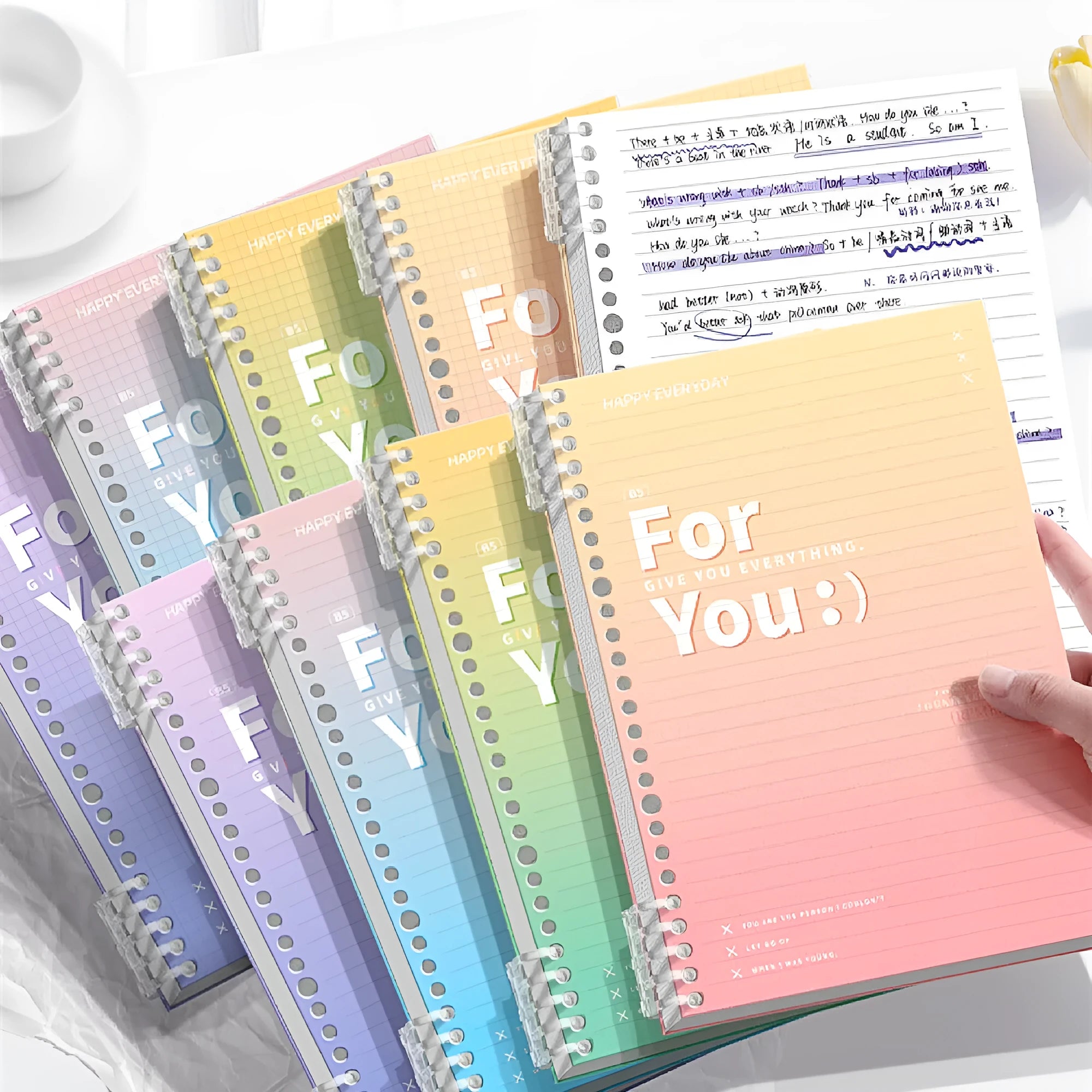 Gradient coloured removable coil spiral notebook in A4 and B5 sizes on a desk.