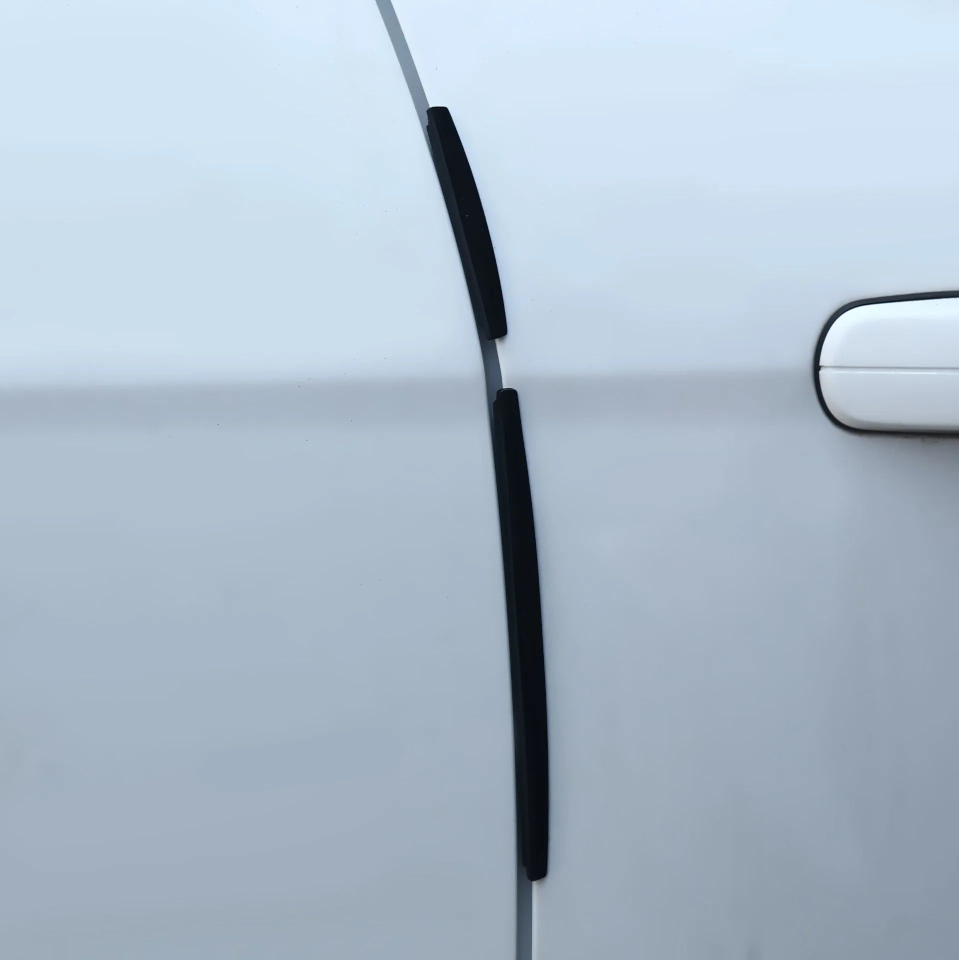 White plastic car door edge protector strip with adhesive backing, shown against a vehicle door.