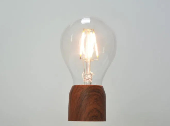 Magnetic levitation floating light bulb with imitation wood base on a table.