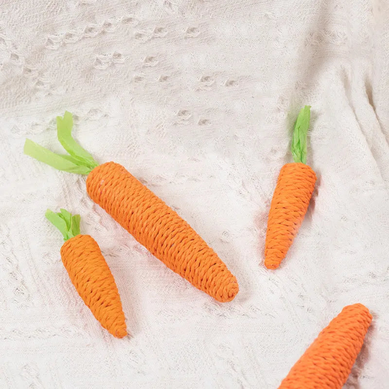Cat toy set with carrot-shaped paper bites, ringing stones, and grinding sticks on soft surface