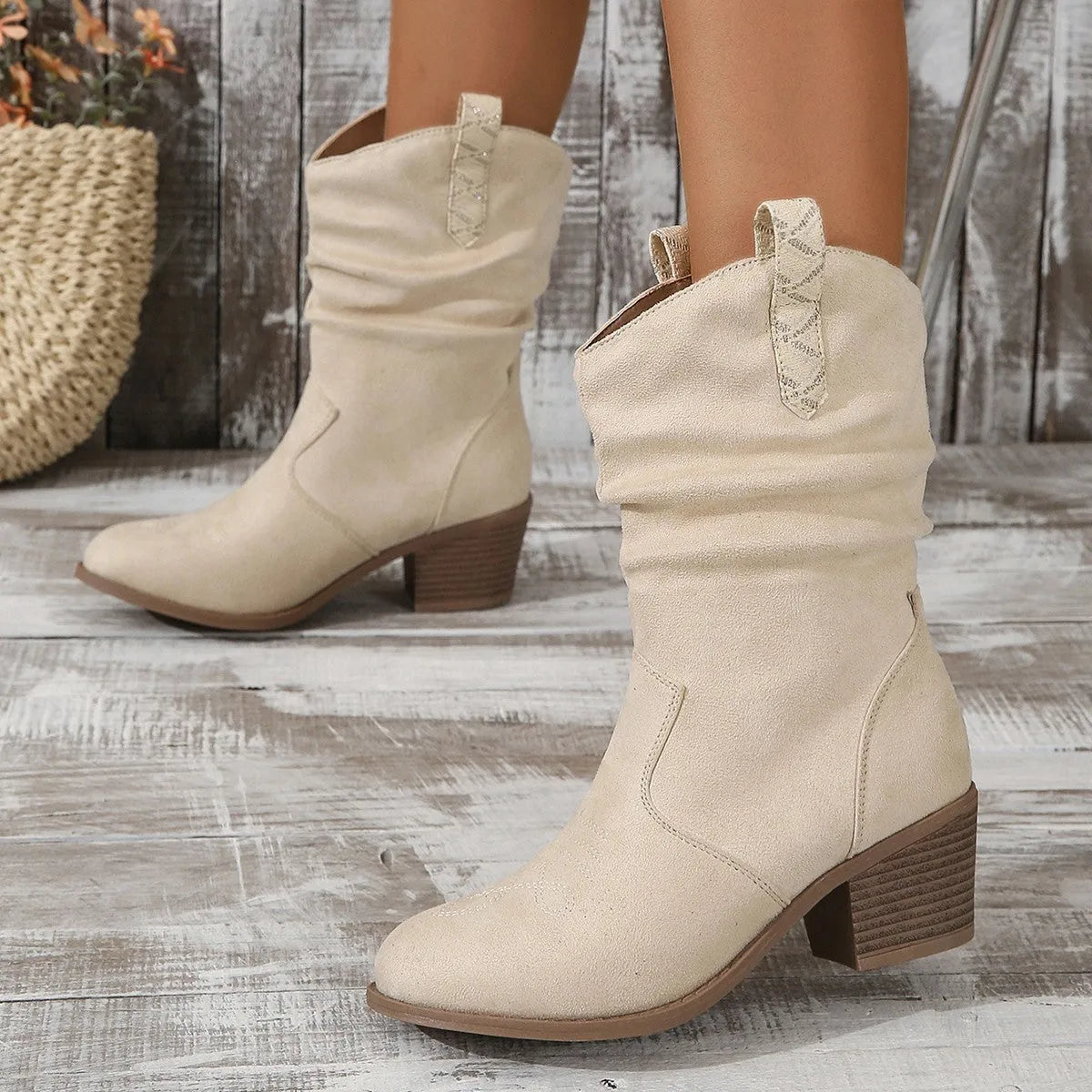Mid-calf suede boots with a block heel on a neutral background, showing leather stitching detail and round toe.