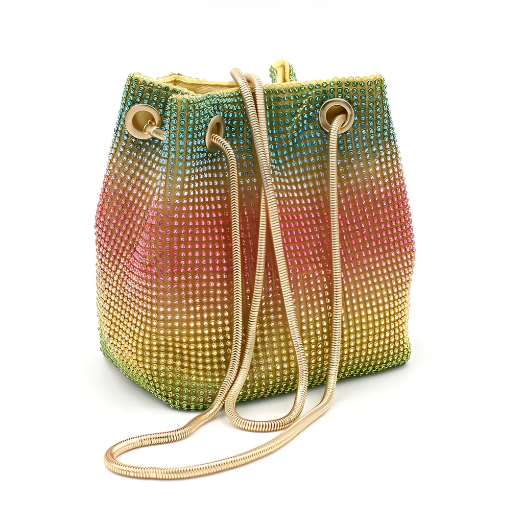 Soft rainbow iridescent bucket bag covered in sparkling rhinestones with a shoulder strap on a white background.