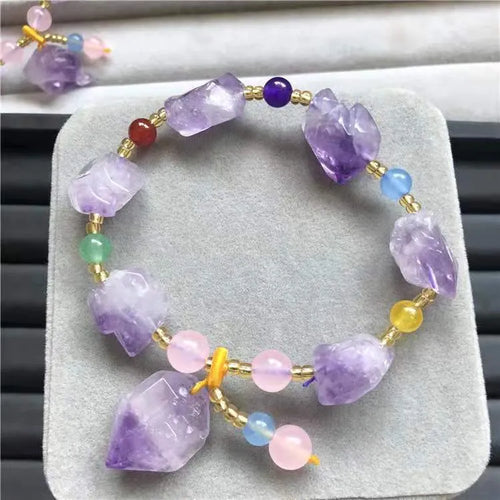 Purple amethyst bracelet with natural shaped beads and a fu character charm on a white background.