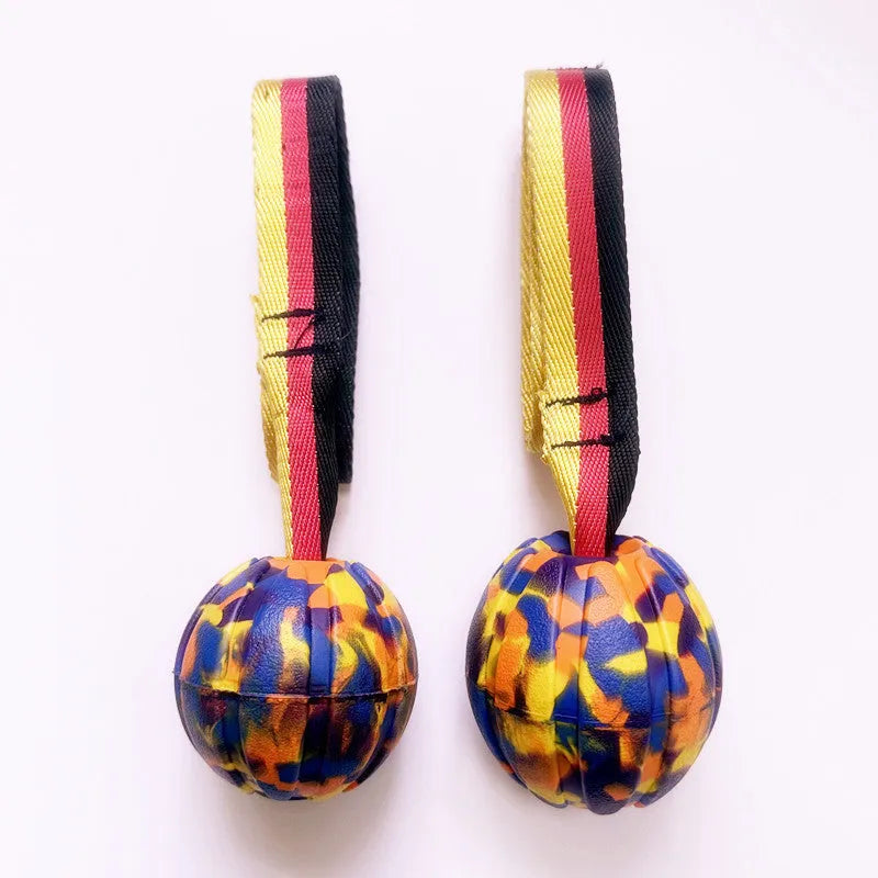 Yellow and camouflage coloured EVA floating dog ball with string in three different sizes on blue background
