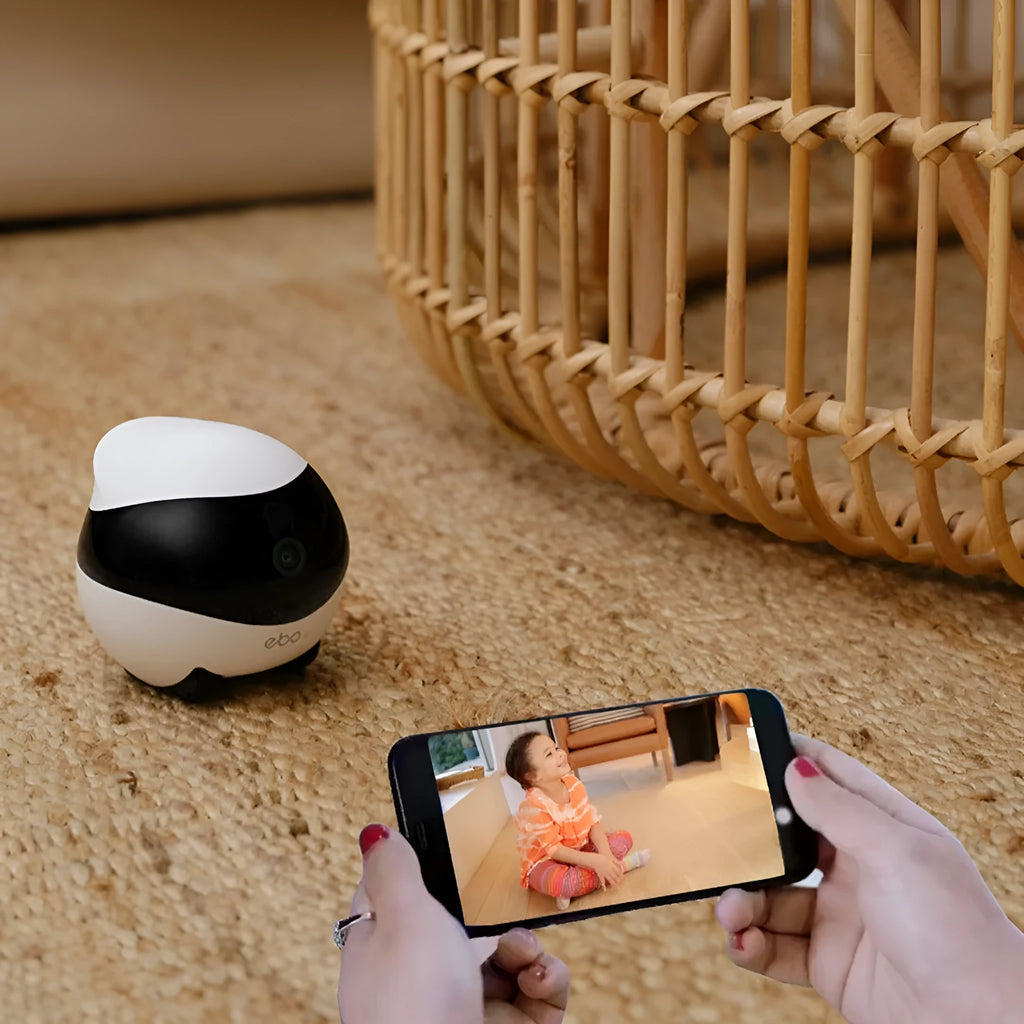 White cube-shaped mobile robot camera with camera lens on a flat surface next to its docking station.