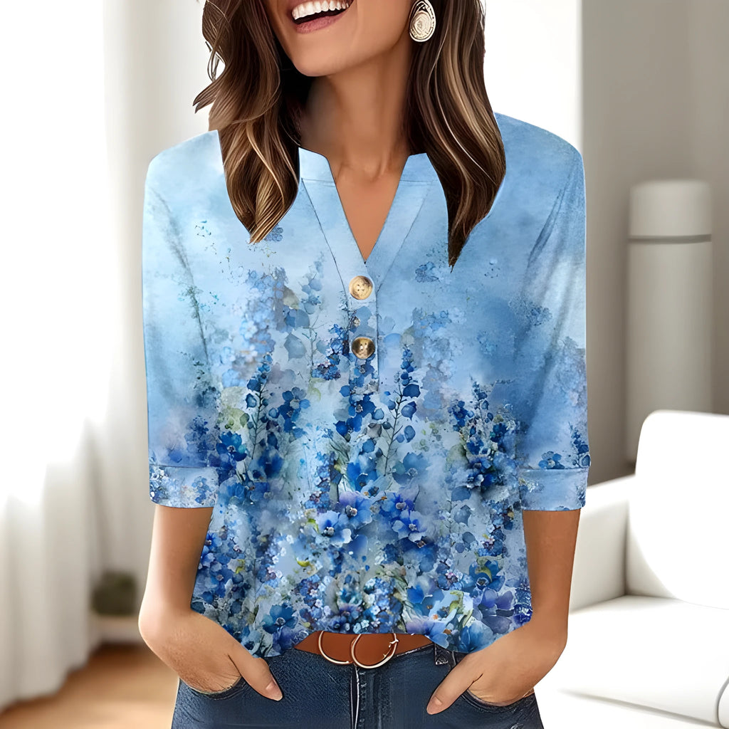 Woman wearing a loose grey V-neck top with a white 3D-effect geometric pattern print.