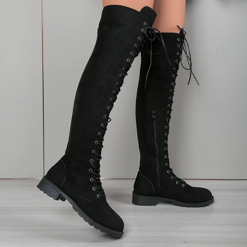 Black lace-up over-the-knee boots with a round toe, flat rubber sole, and decorative stitching on the shaft.