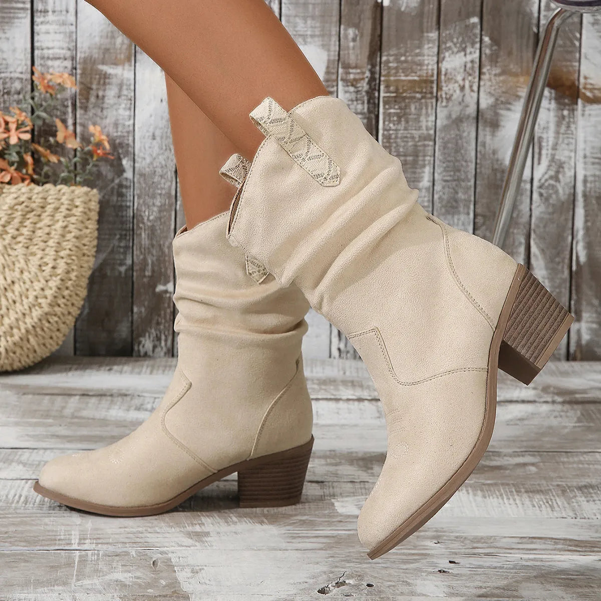Mid-calf suede boots with a block heel on a neutral background, showing leather stitching detail and round toe.