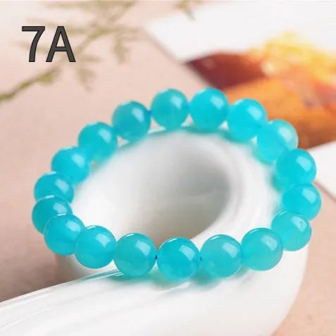 Loose natural green Amazonite beads in various sizes for jewellery making on a white surface.
