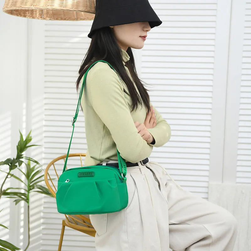 Pleated Oxford cloth horizontal messenger bag in cangling green, showing cross-body strap and external pocket.
