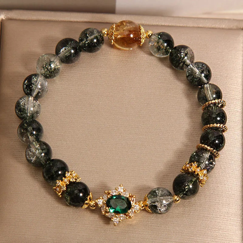 Gold electroplated women's bracelet with a green phantom quartz stone, ruby accents, rhinestones, and pearls.