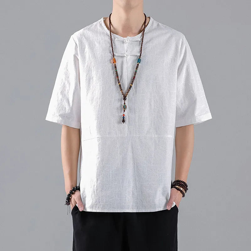 Man wearing a black loose-fit linen t-shirt with a retro jacquard pattern and fastener decoration.