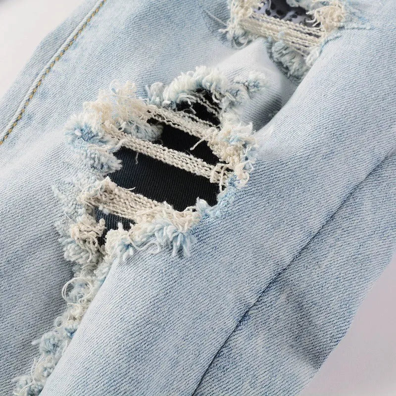 Light blue slim fit men's jeans with patch details, holes, and enzyme-washed finish