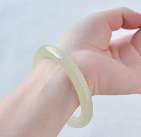 Ice silk jade round bar bracelet on a wrist, showing its smooth, continuous loop and polished stone finish.