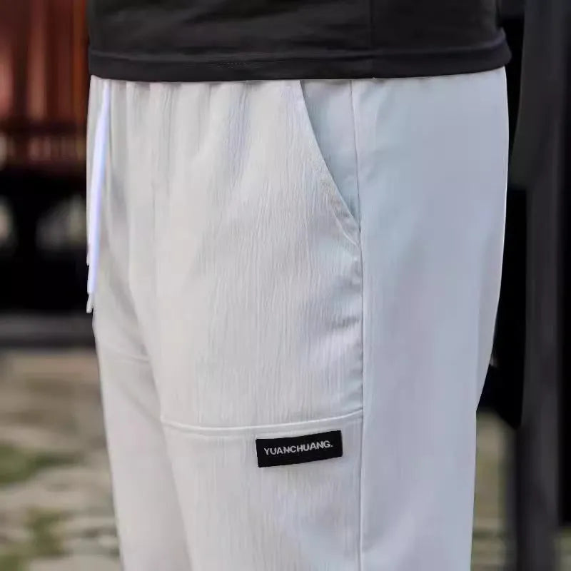 Men's straight-leg polyester trousers in light grey on a hanger