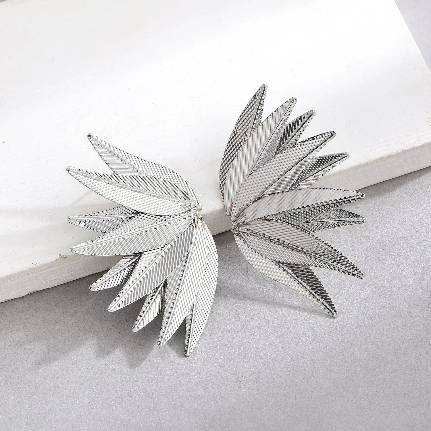 Alloy metal leaf silhouette earrings in white and gold colour options showing botanical jewellery design