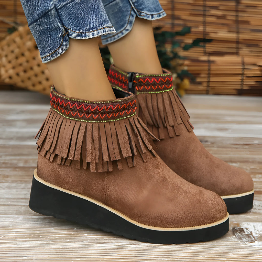 Women's black suede wedge bootie with a thick sole, side zipper, and tassel detail.