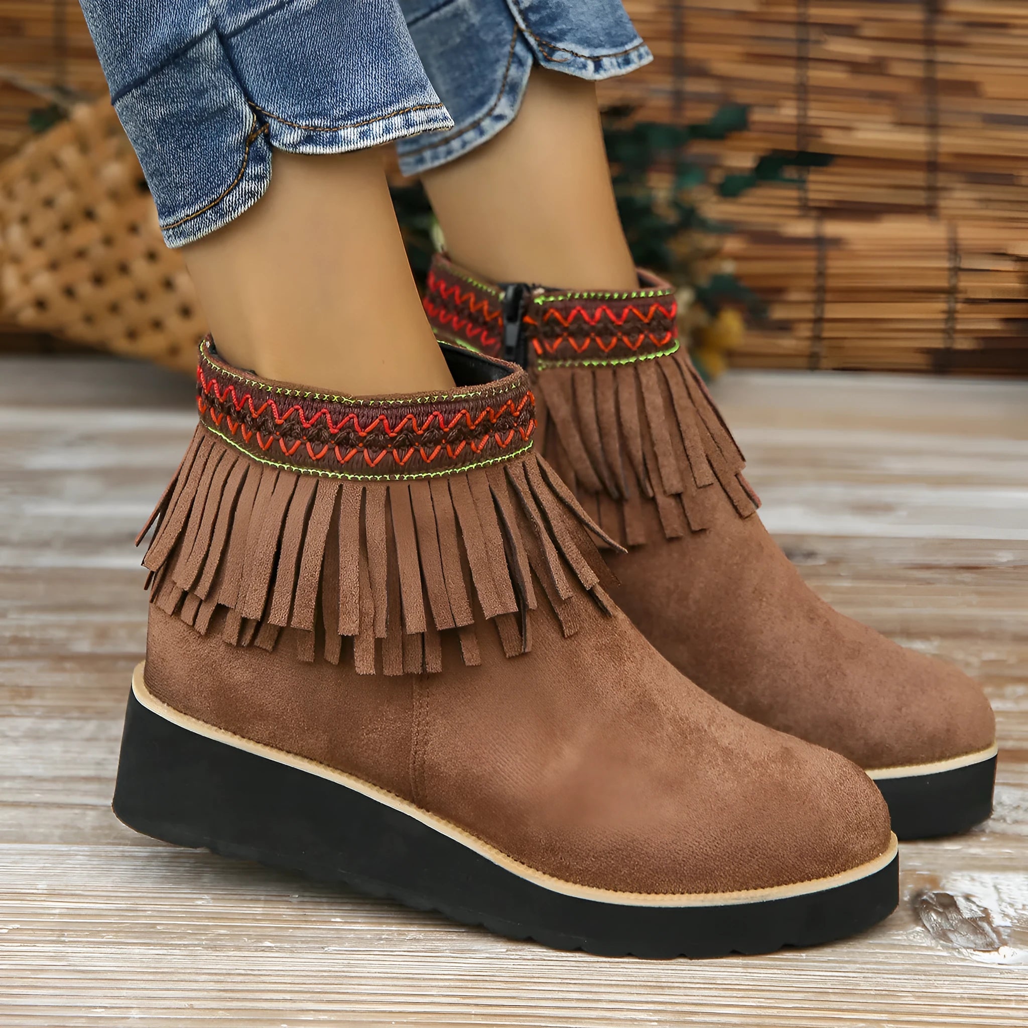 Women's black suede wedge bootie with a thick sole, side zipper, and tassel detail.