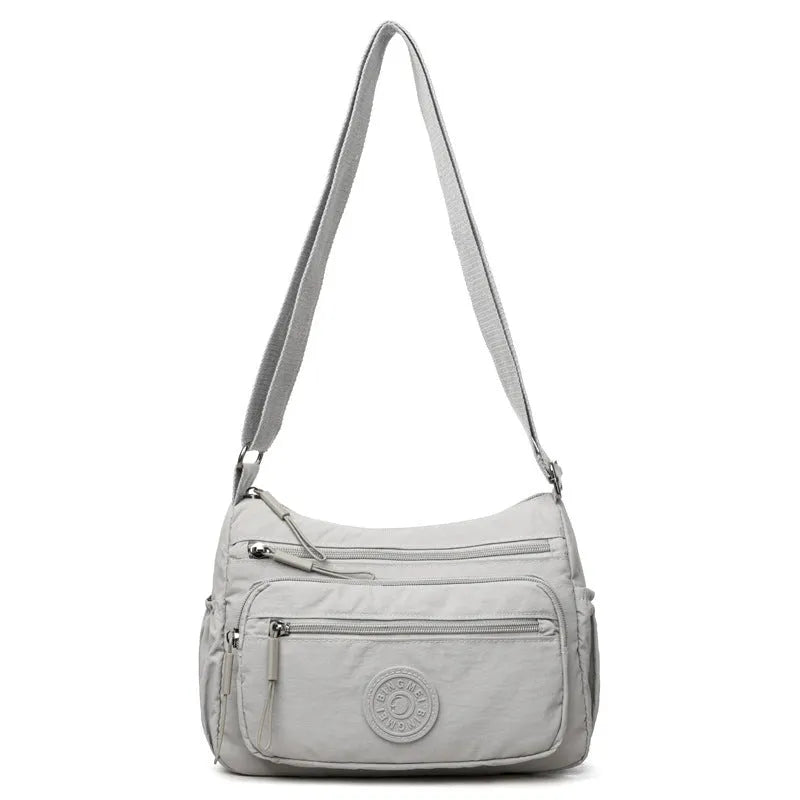 Soft water-repellent nylon crossbody bag with a three-dimensional front pocket and adjustable strap.