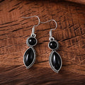 A pair of black and purple vintage geometric drop earrings with a round detail, shown against a plain background.