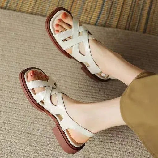 Women's glossy patent leather sandals with a square toe and low heel on a solid colour background.