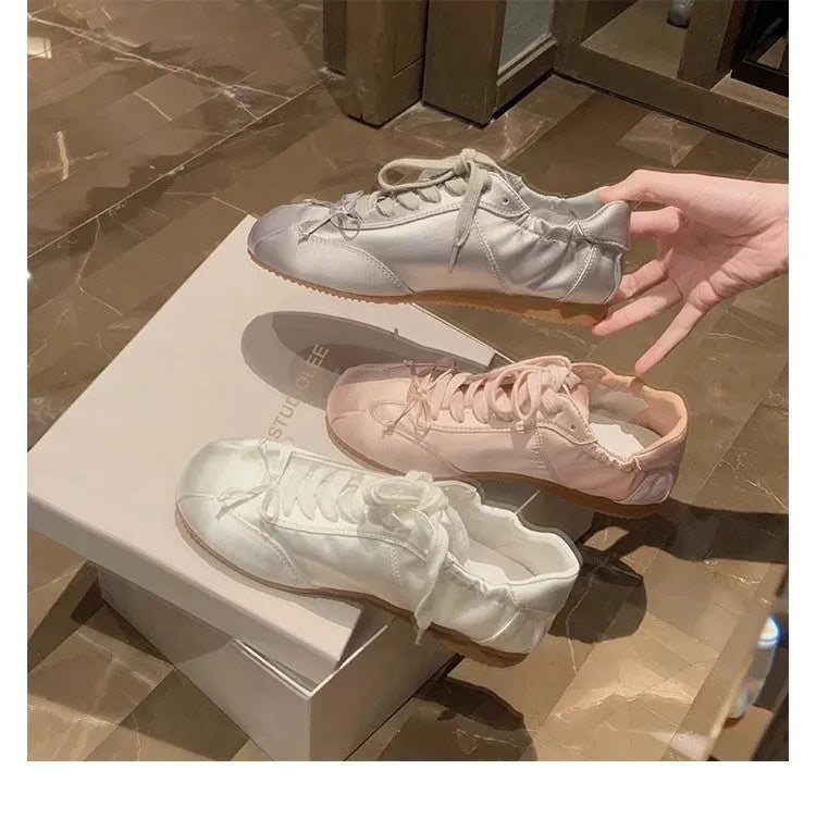 Women's silver grey satin ballet flat shoes with front lace-up design and round toe.
