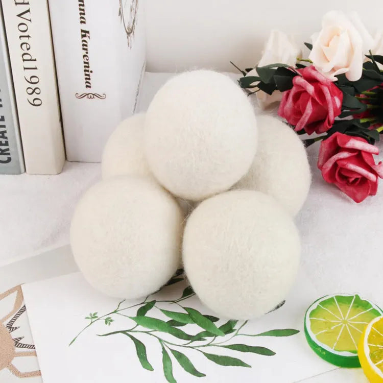 Set of 100% wool felt laundry drying balls in various sizes next to a plain cotton storage bag.