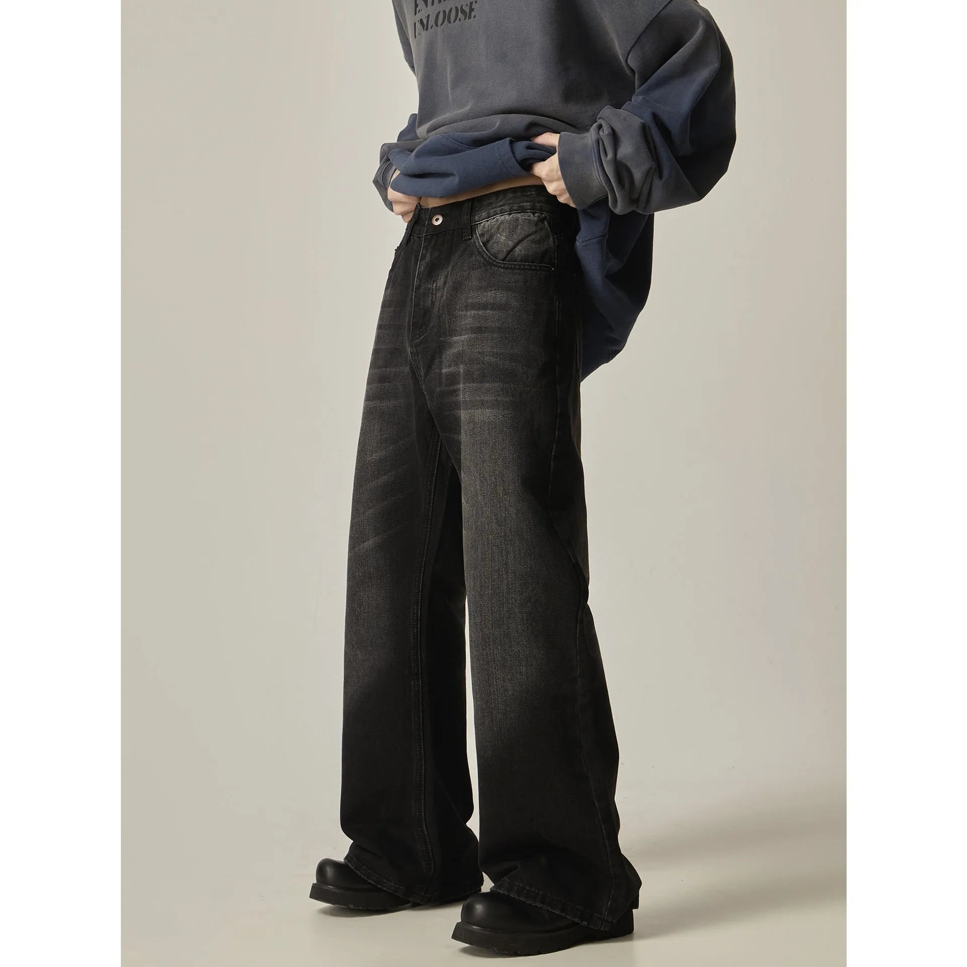 Black loose-fit straight leg denim jeans with a zipper fly on a neutral background.