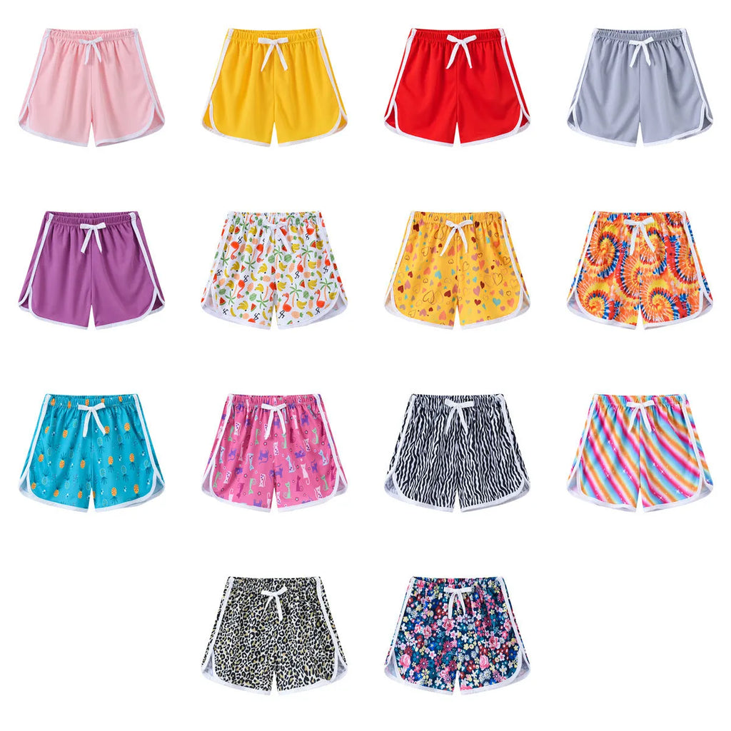Children's polyester shorts in assorted colours and prints including pineapple, kitten, and stripe designs.