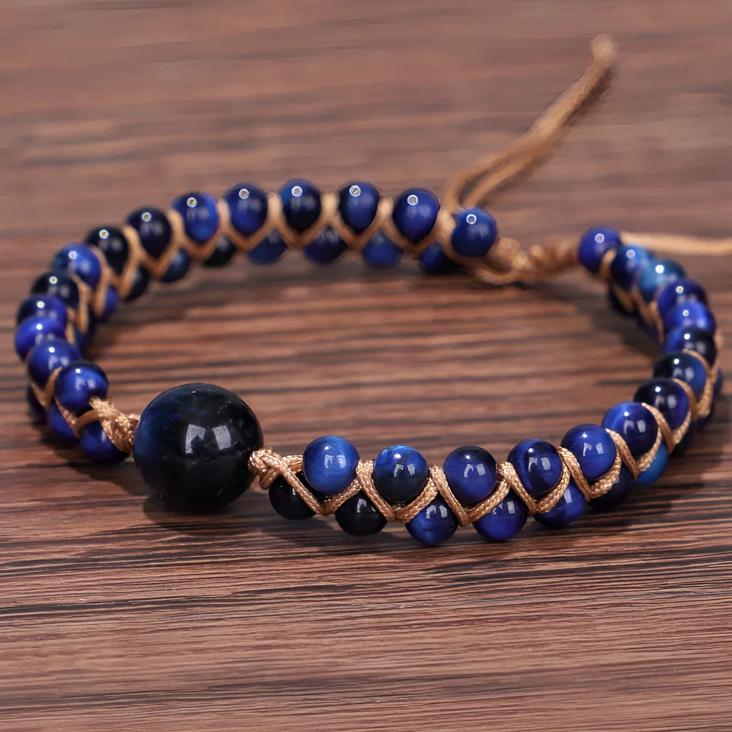 Close-up of a handmade woven bracelet featuring blue tigereye beads in a geometric pattern on a wrist.