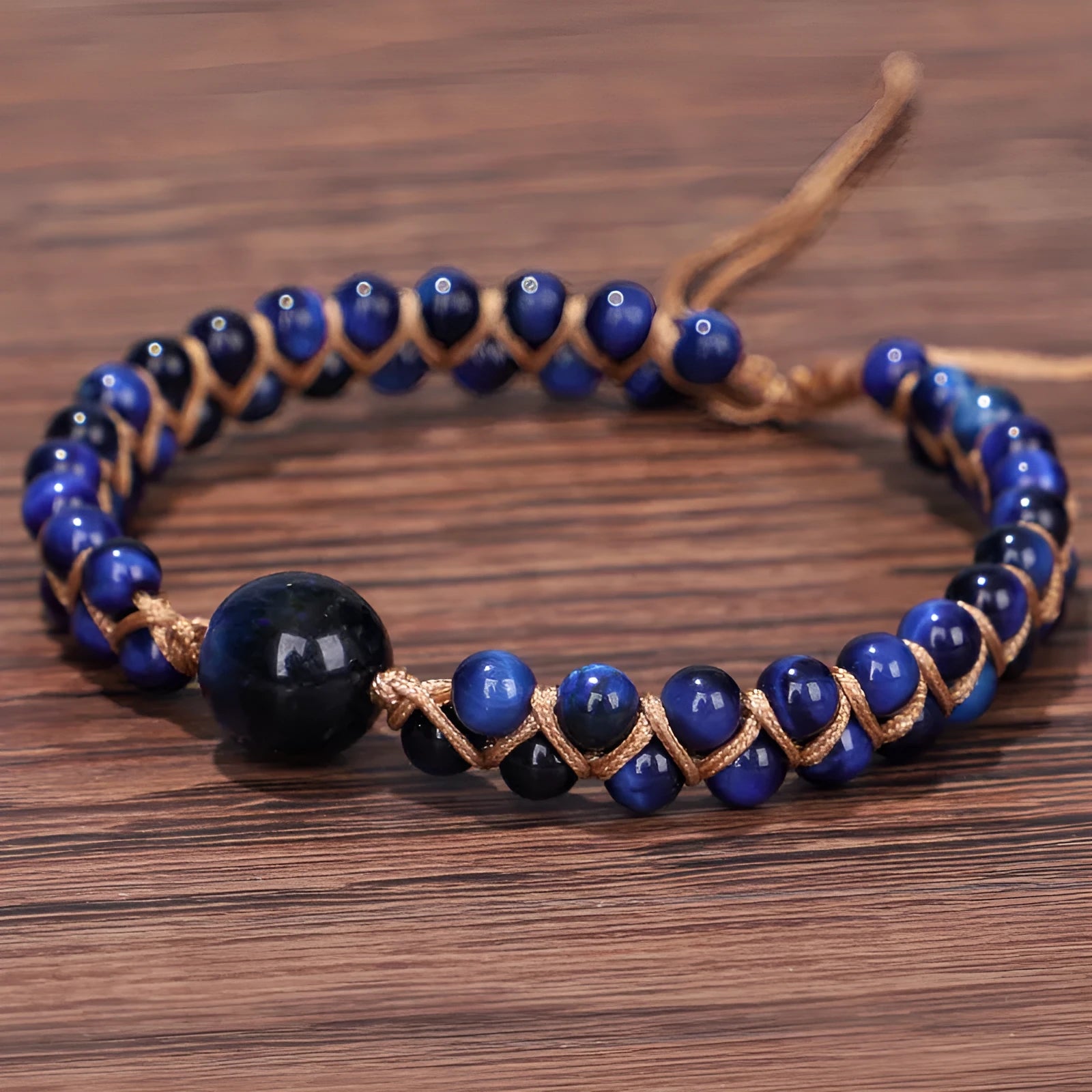 Close-up of a handmade woven bracelet featuring blue tigereye beads in a geometric pattern on a wrist.