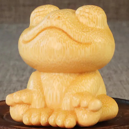 Solid bamboo carving of a smiling cartoon frog ornament, 5cm tall.