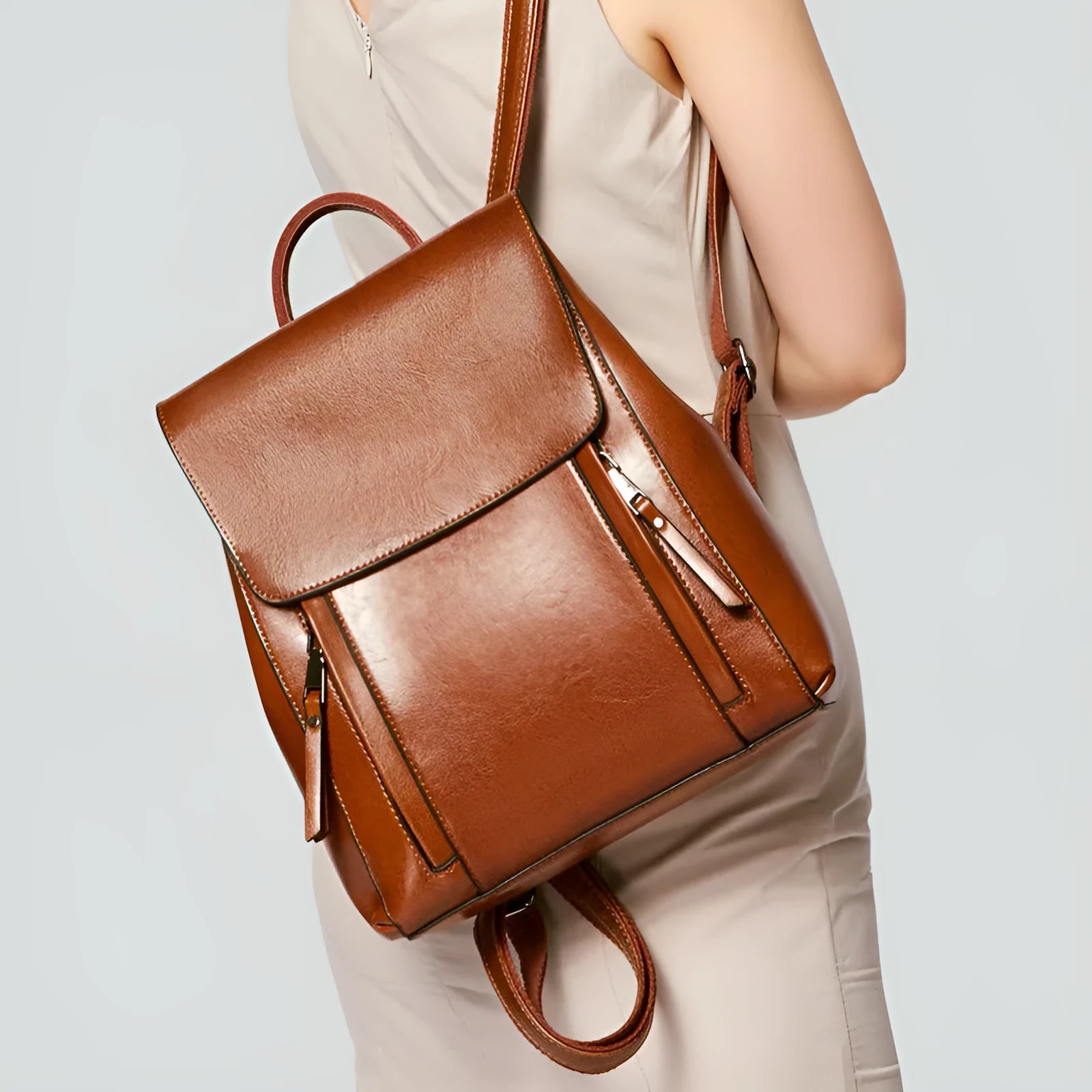 Black genuine cowhide leather women's backpack with double straps and a flap cover, showing internal zipper and phone pockets.
