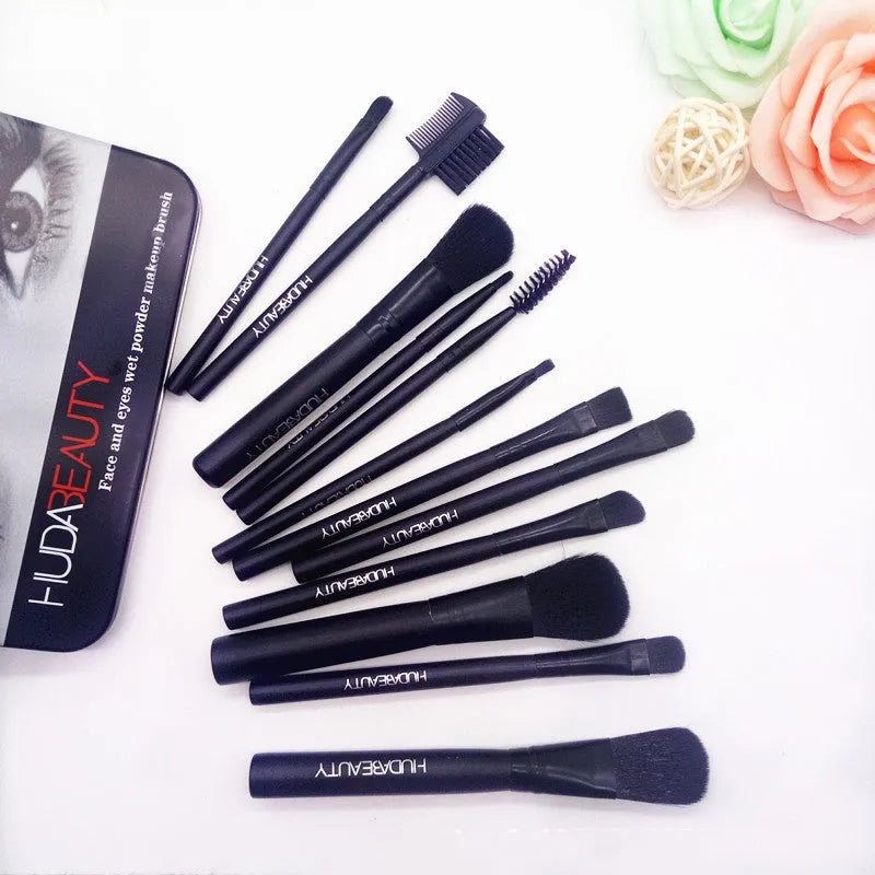 12 makeup brushes with corrugated silk nylon bristles and wooden handles in a black tin box on a flat surface.