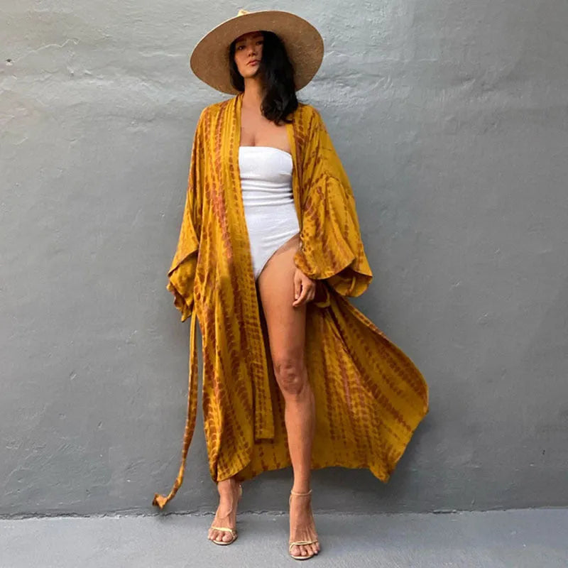 A woman wearing a loose, printed cotton cover-up blouse over swimwear at the beach.