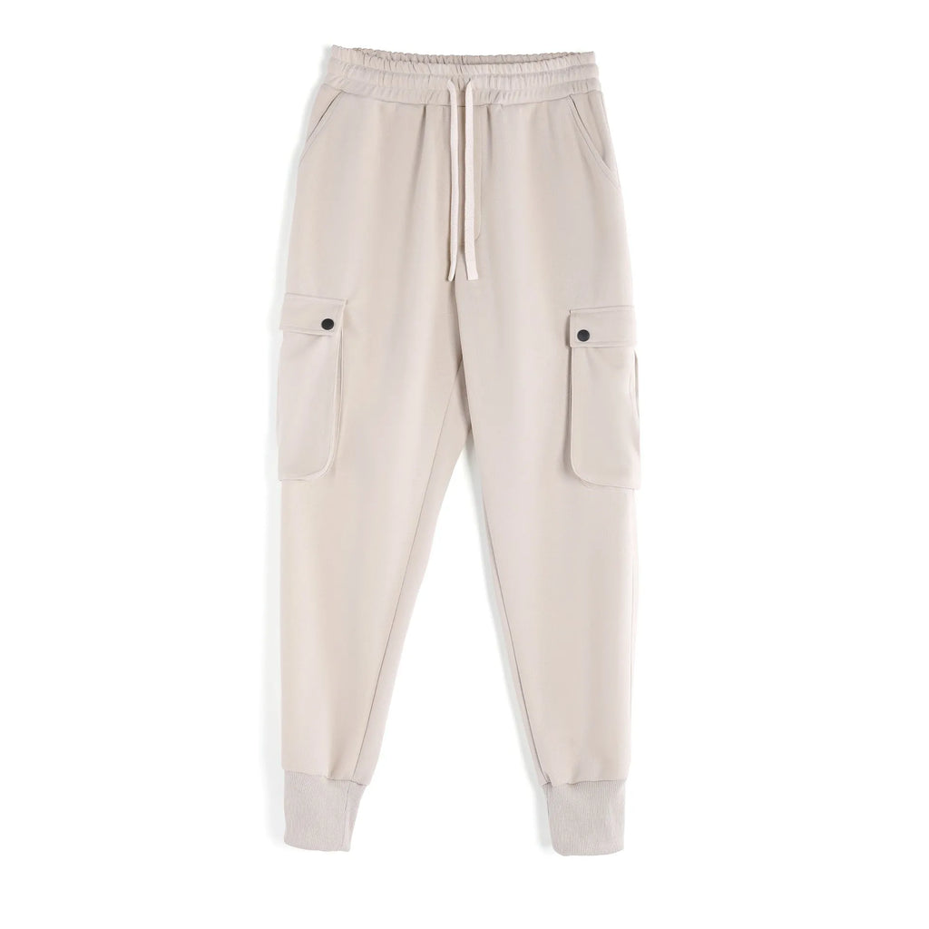Men's loose-fit beige cotton trousers with tied ankle cuffs and multiple pockets on the legs.