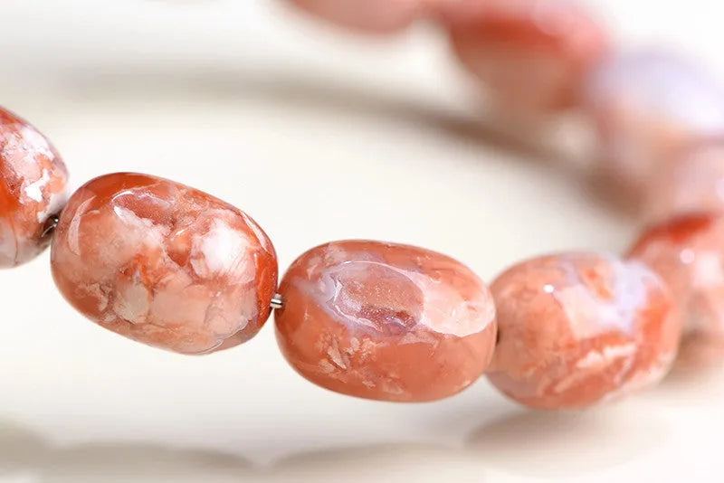 Natural cherry agate bracelet with geometric 10x14mm barrel beads and ruyi details on a wrist.