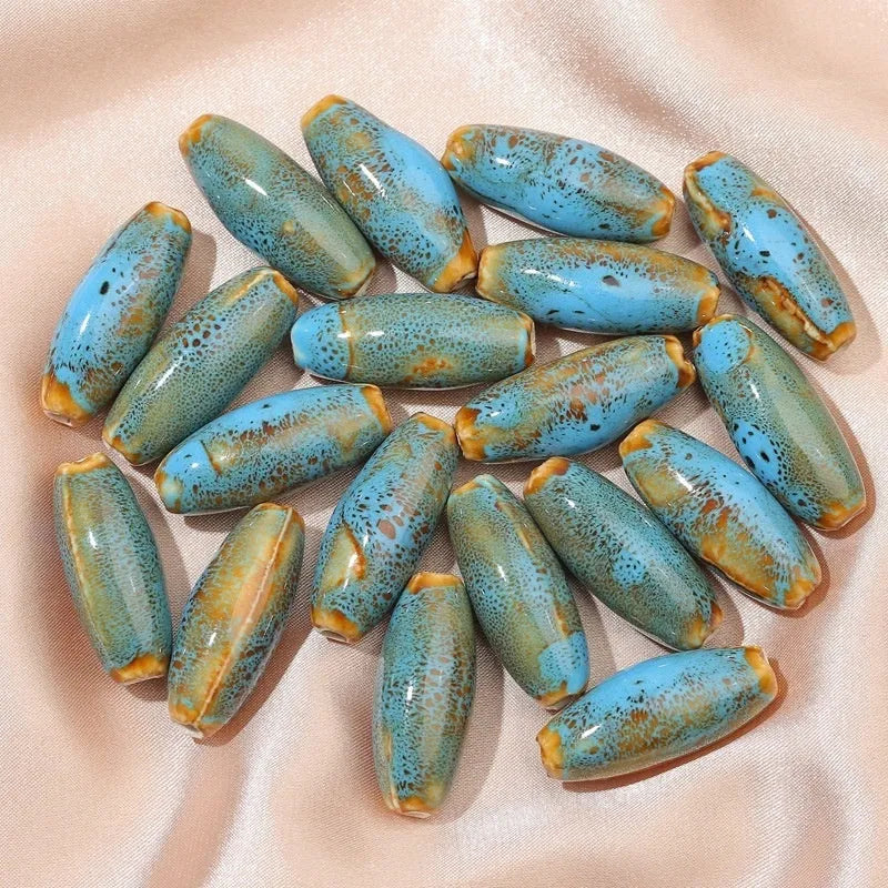 Assortment of ceramic bullet beads in pink, yellow, blue, red, coffee, green, orange, and mixed flower glaze colours.