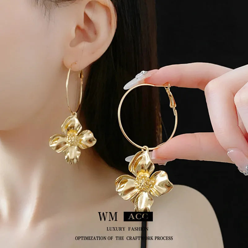Close-up of silver needle floral geometric drop earrings in gold electroplated metal.