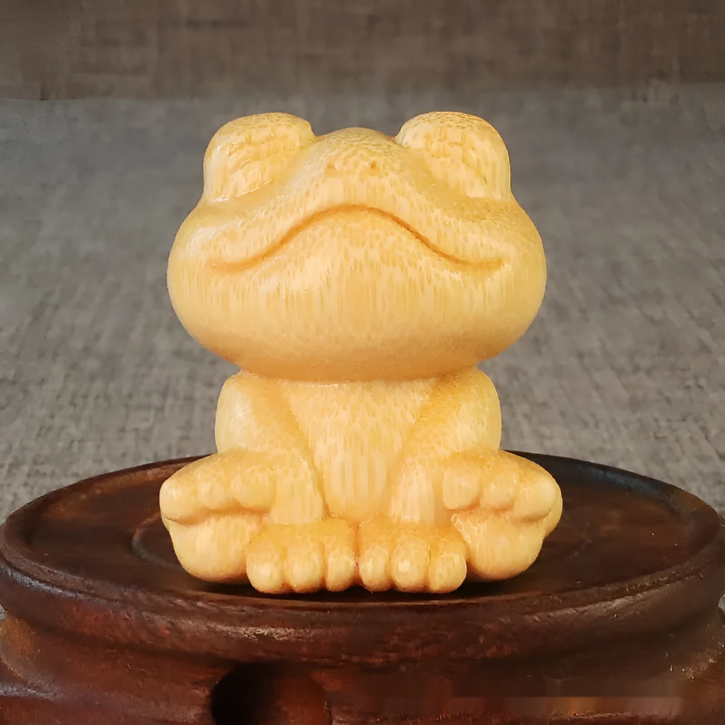 Solid bamboo carving of a smiling cartoon frog ornament, 5cm tall.