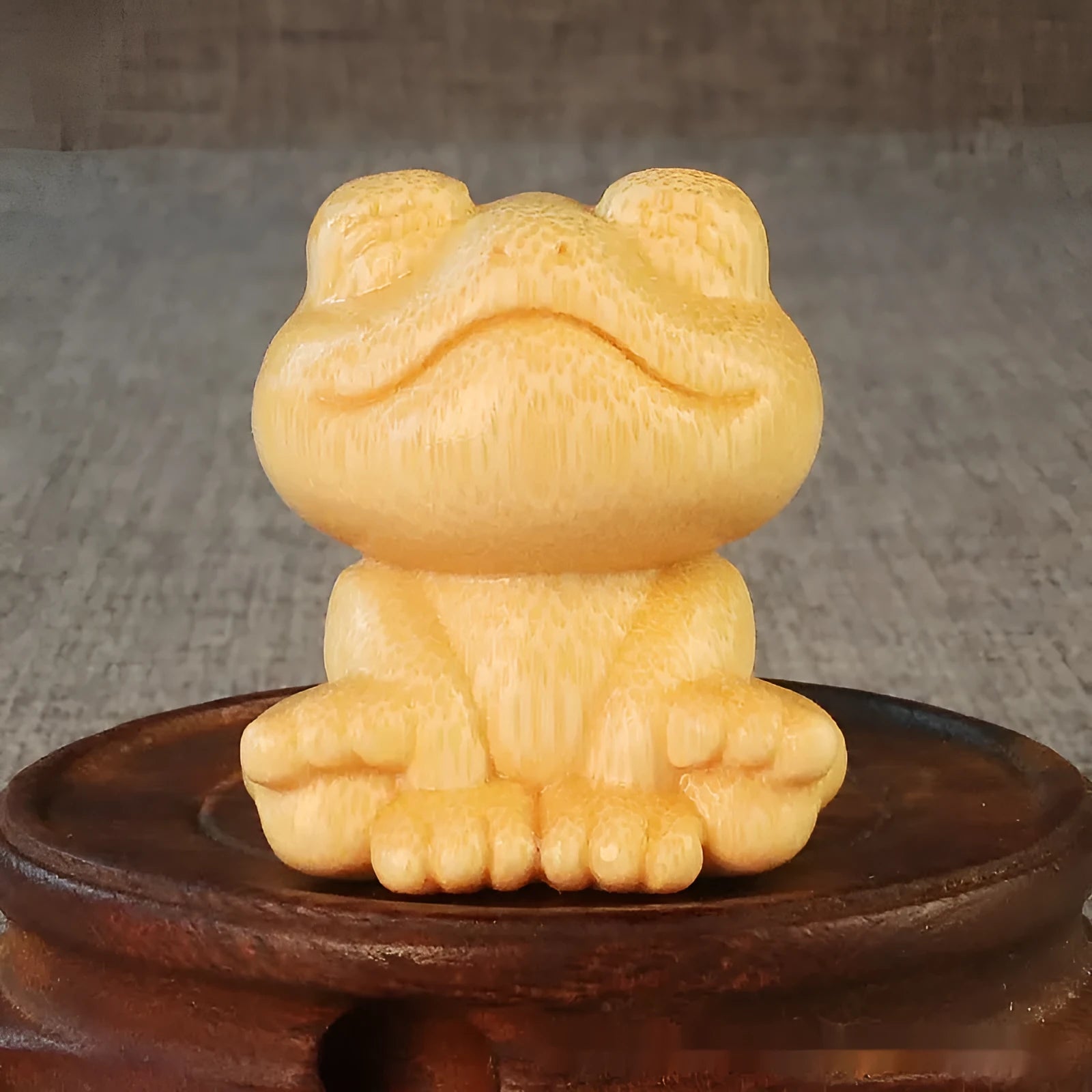 Solid bamboo carving of a smiling cartoon frog ornament, 5cm tall.