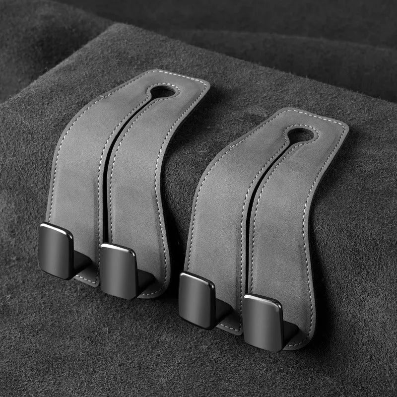 Alloy car seat hook clipped to headrest post in black, showing flip-down design for bag storage.