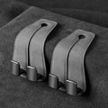 Alloy car seat hook clipped to headrest post in black, showing flip-down design for bag storage.