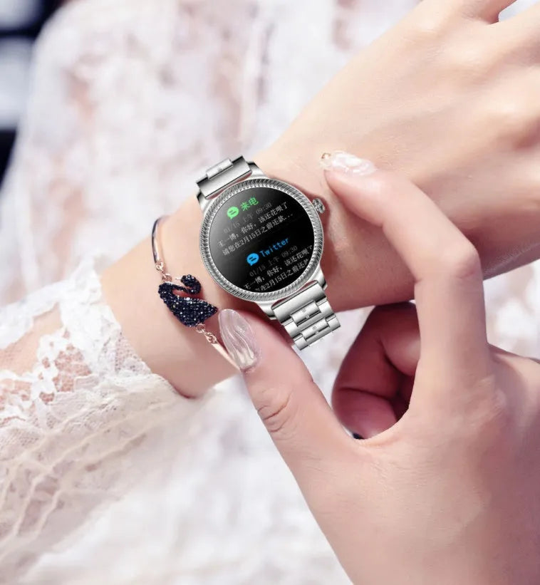 AK38 ladies smartwatch with stainless steel band on a wrist, showing its colour screen display.