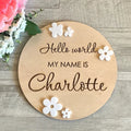 Personalised square wooden baby name plaque showing engraved birth details, in a rustic style, against a nursery background.