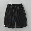 Men's loose fit linen shorts in green, showing straight drooping leg and drawstring waist.