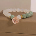 White agate floral bracelet with jade details and adjustable clasp on woman's wrist